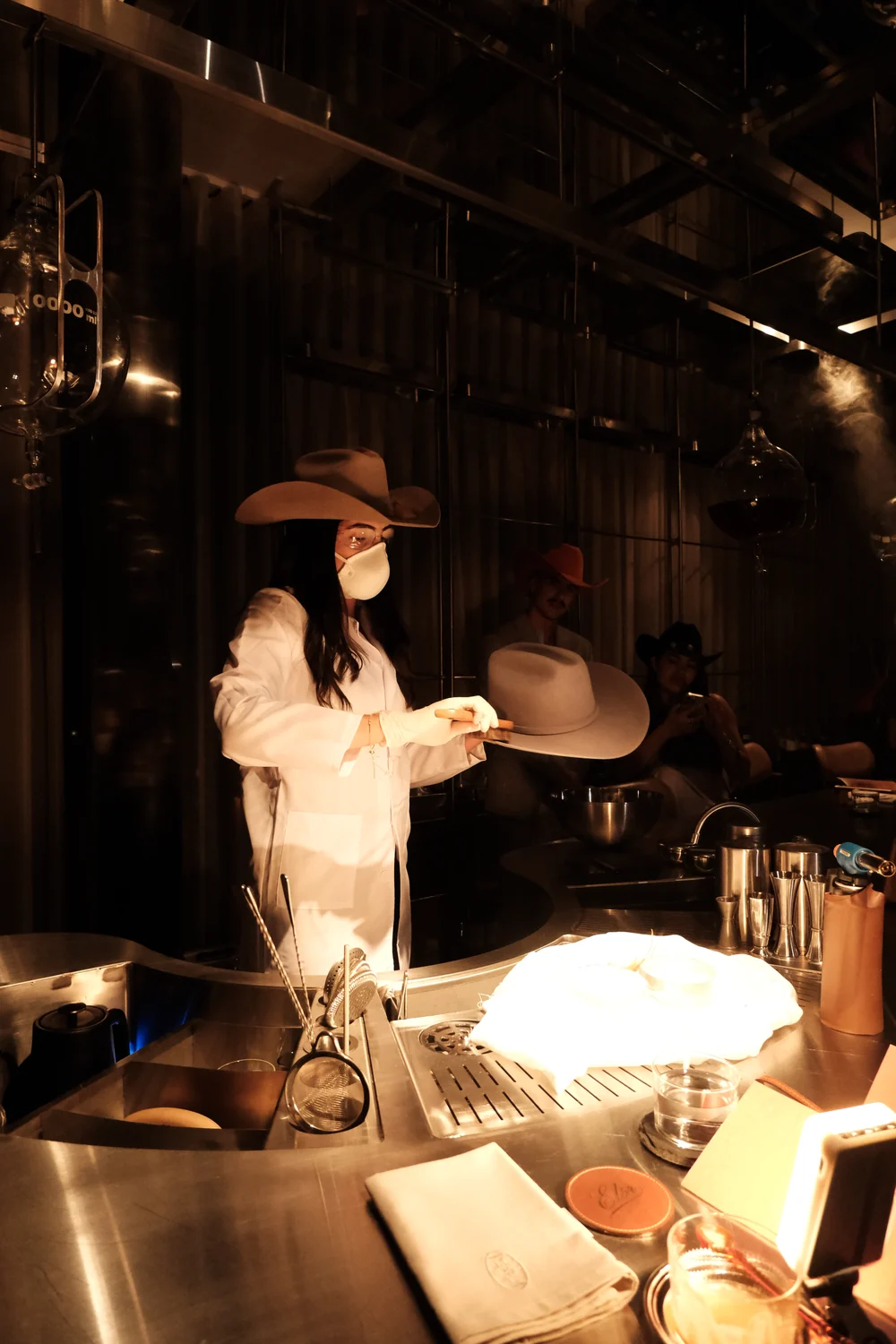 Artesana de ELÓR con sombrero cowboy marcando una pieza en vivo tras la barra de un evento