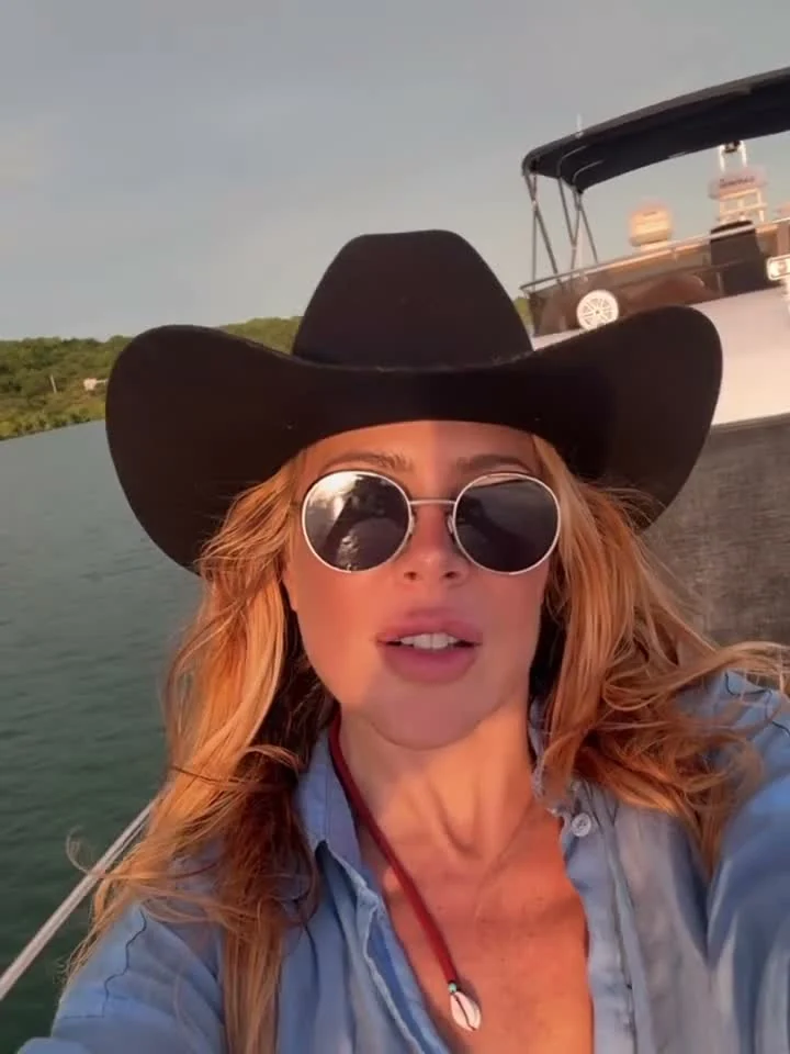 Mujer con sombrero cowboy negro y gafas redondas en un barco a la luz dorada