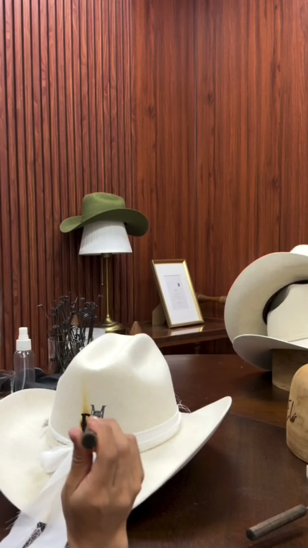 Artesano grabando a fuego un monograma en el sombrero cowboy blanco de la novia