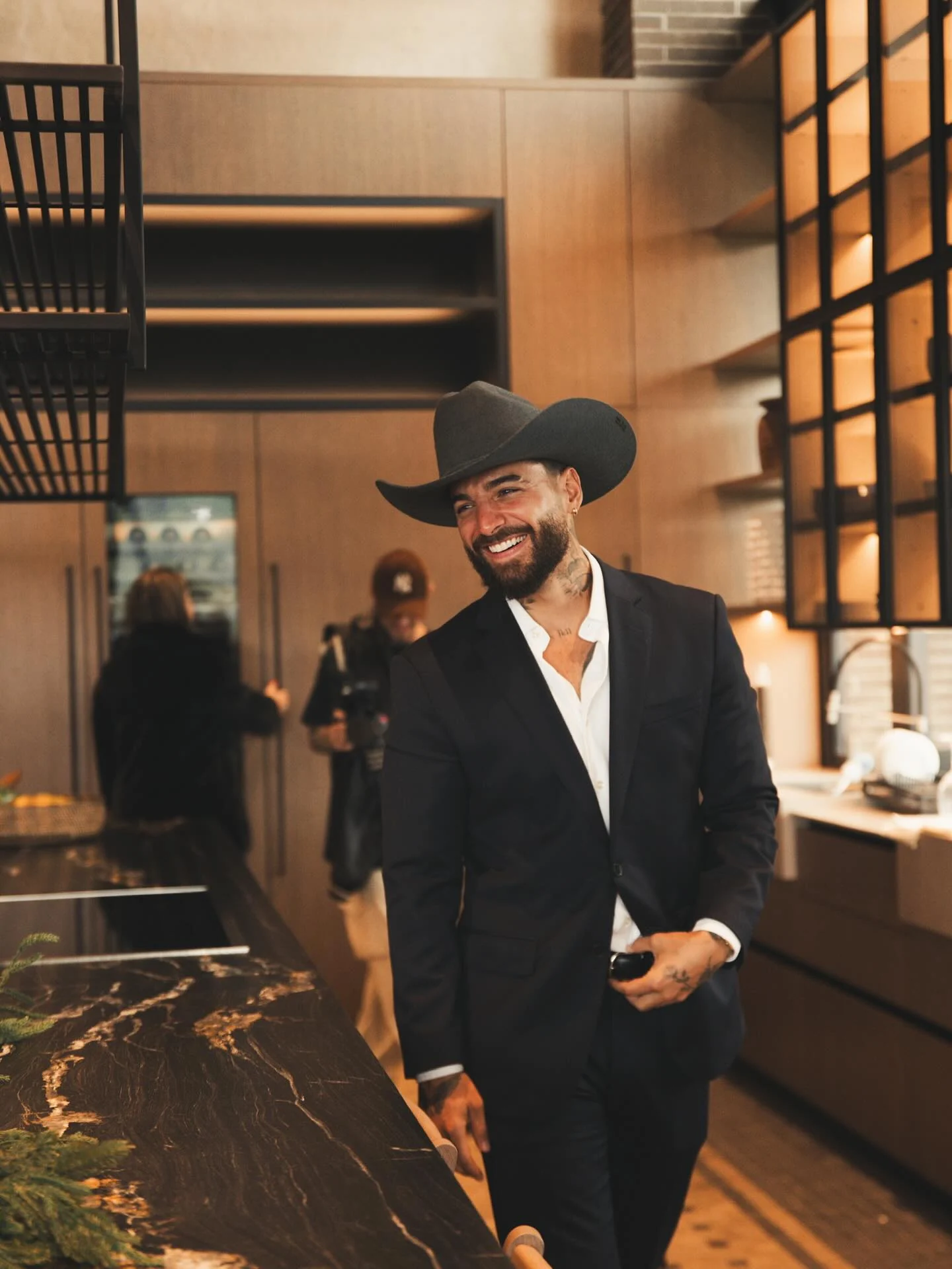 Hombre de traje oscuro y sombrero cowboy negro en una reunión navideña
