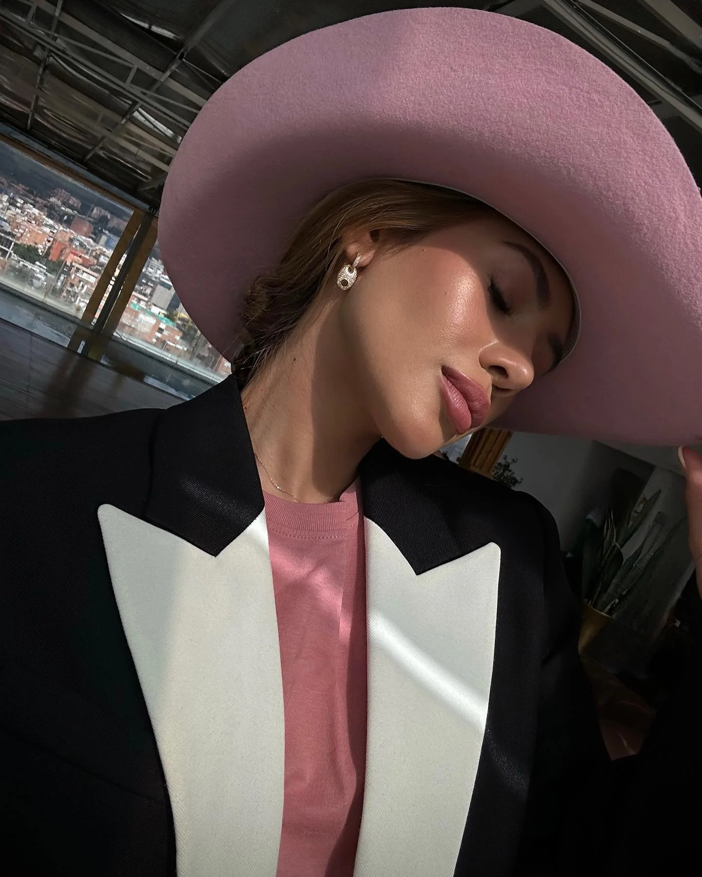 Perfil con sombrero rosa de ala ancha y blazer negro