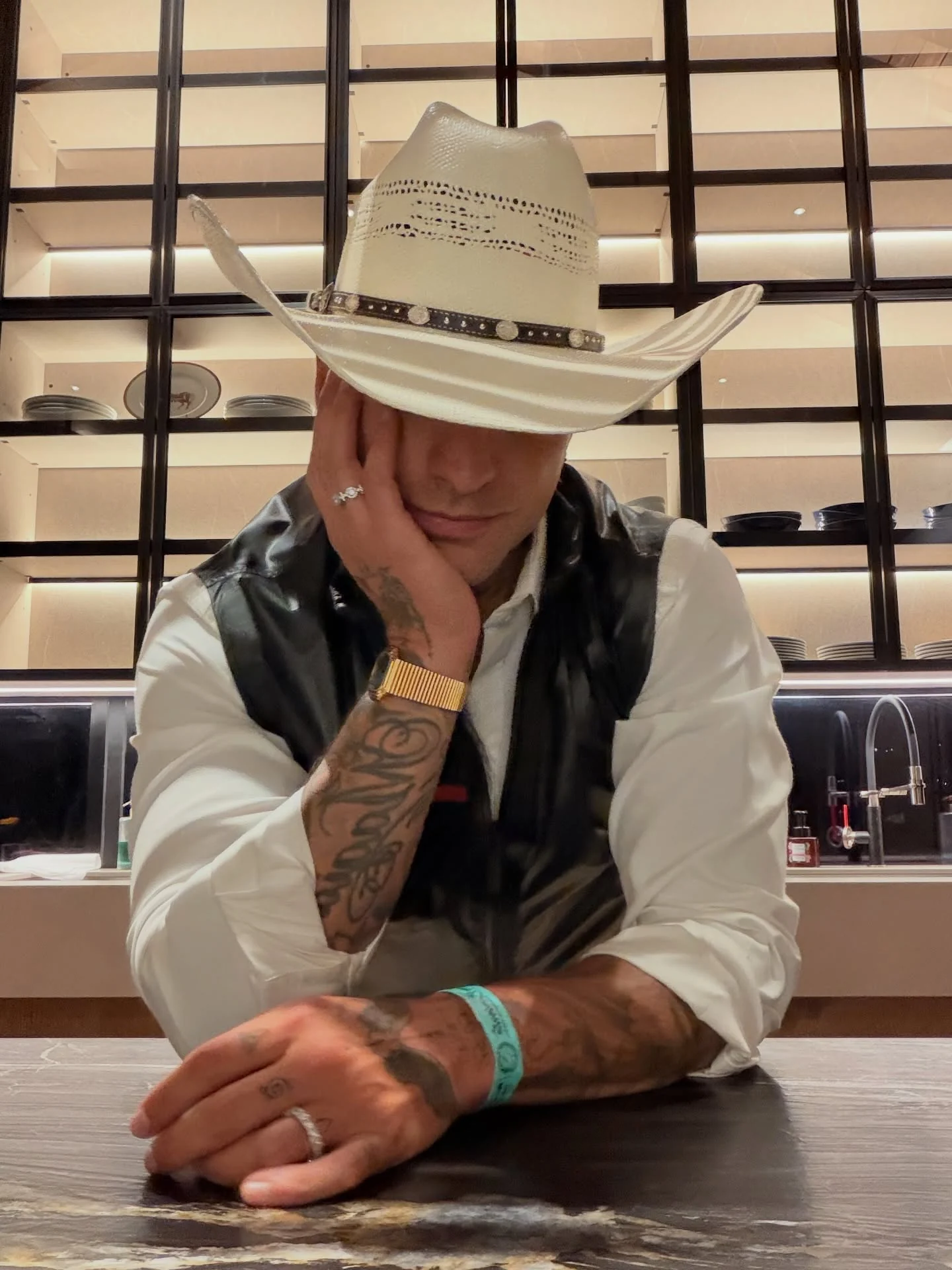 Artista con sombrero cowboy blanco apoyado en el counter de un showroom