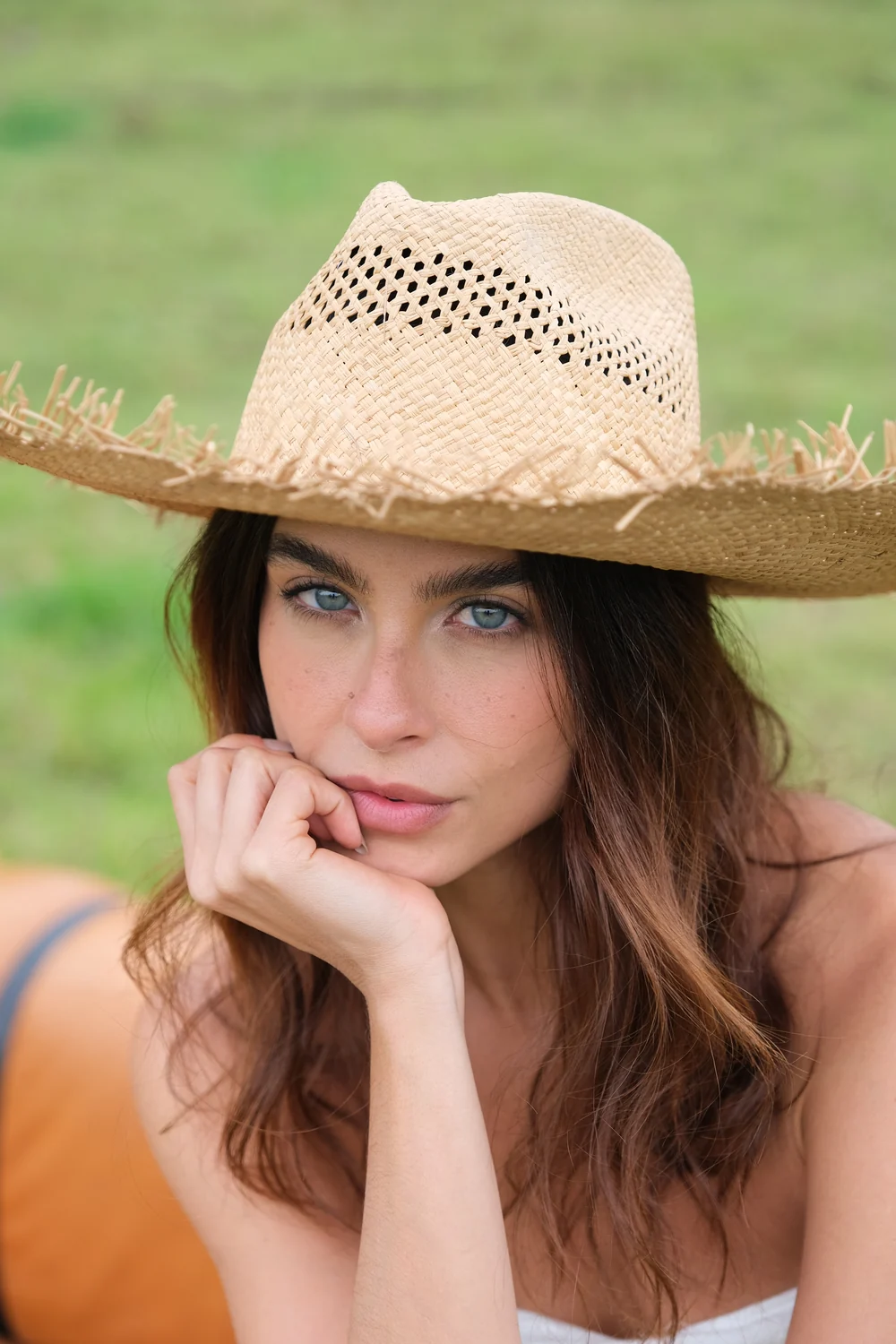 Modelo con sombrero de paja de ala ancha sobre fondo verde
