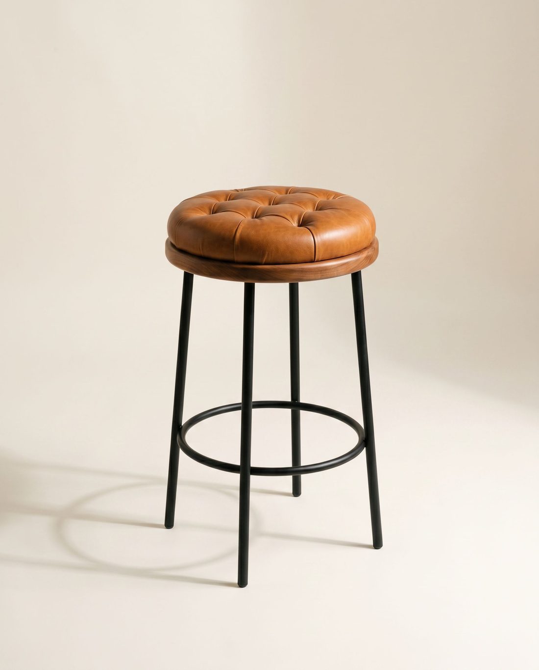 HABANA, taburete de bar con asiento capitoné en cuero cognac, aro de madera y patas metálicas negras, retrato de estudio