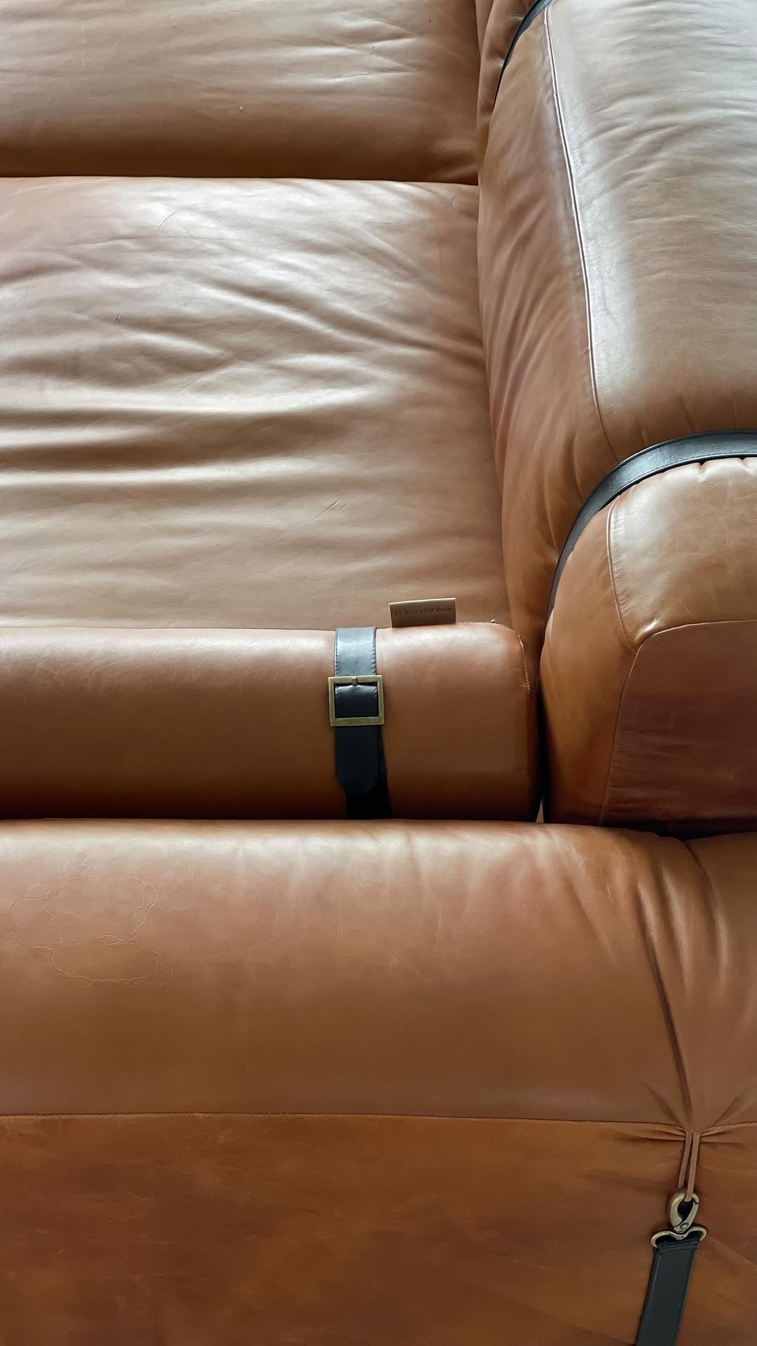 Detalle del cuero cognac y las correas con hebilla de un sofá modular recién entregado