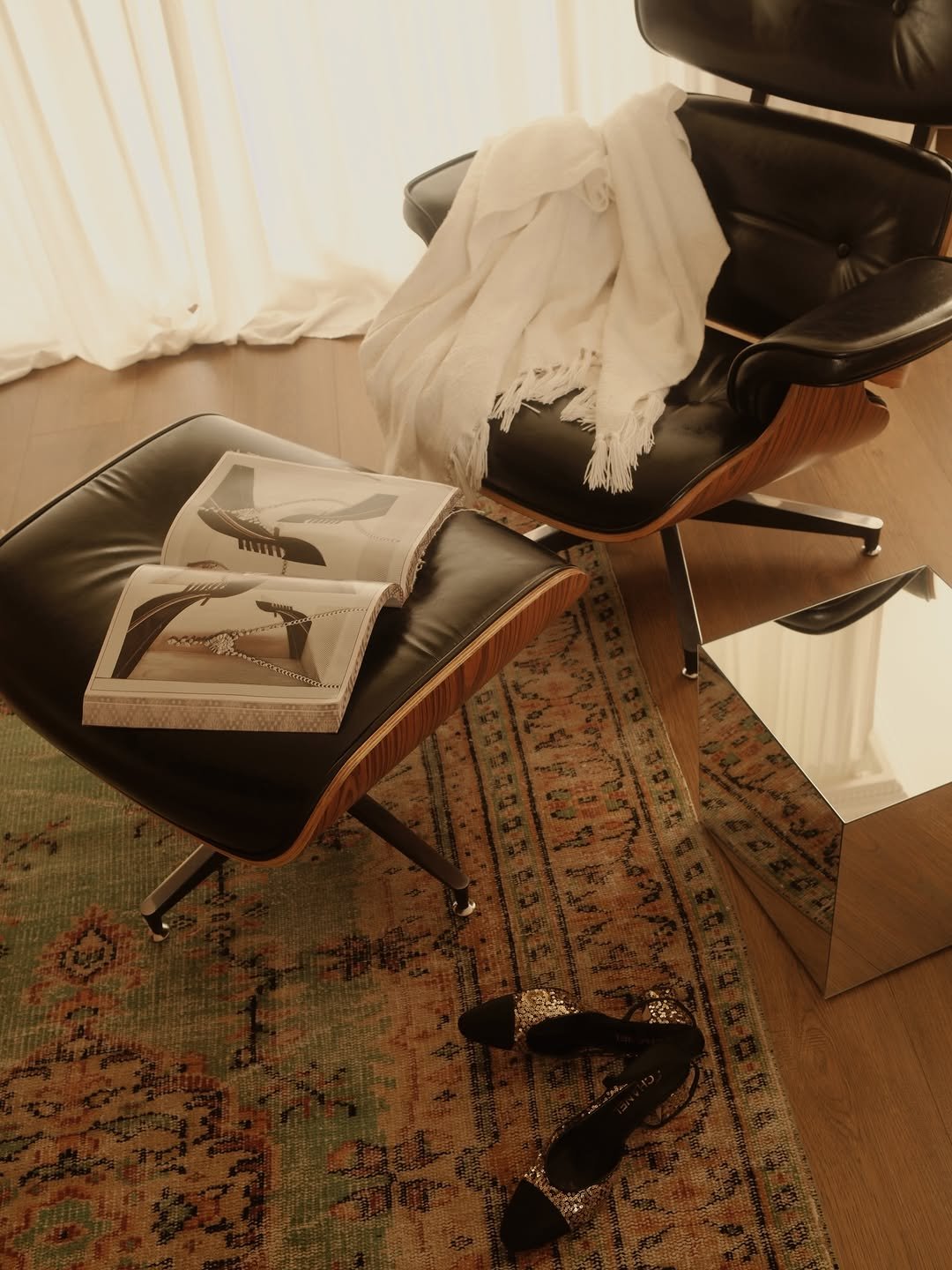 La esquina de lectura de @sisterlystyle: lounge de cuero negro y madera con una manta blanca, junto a la ventana